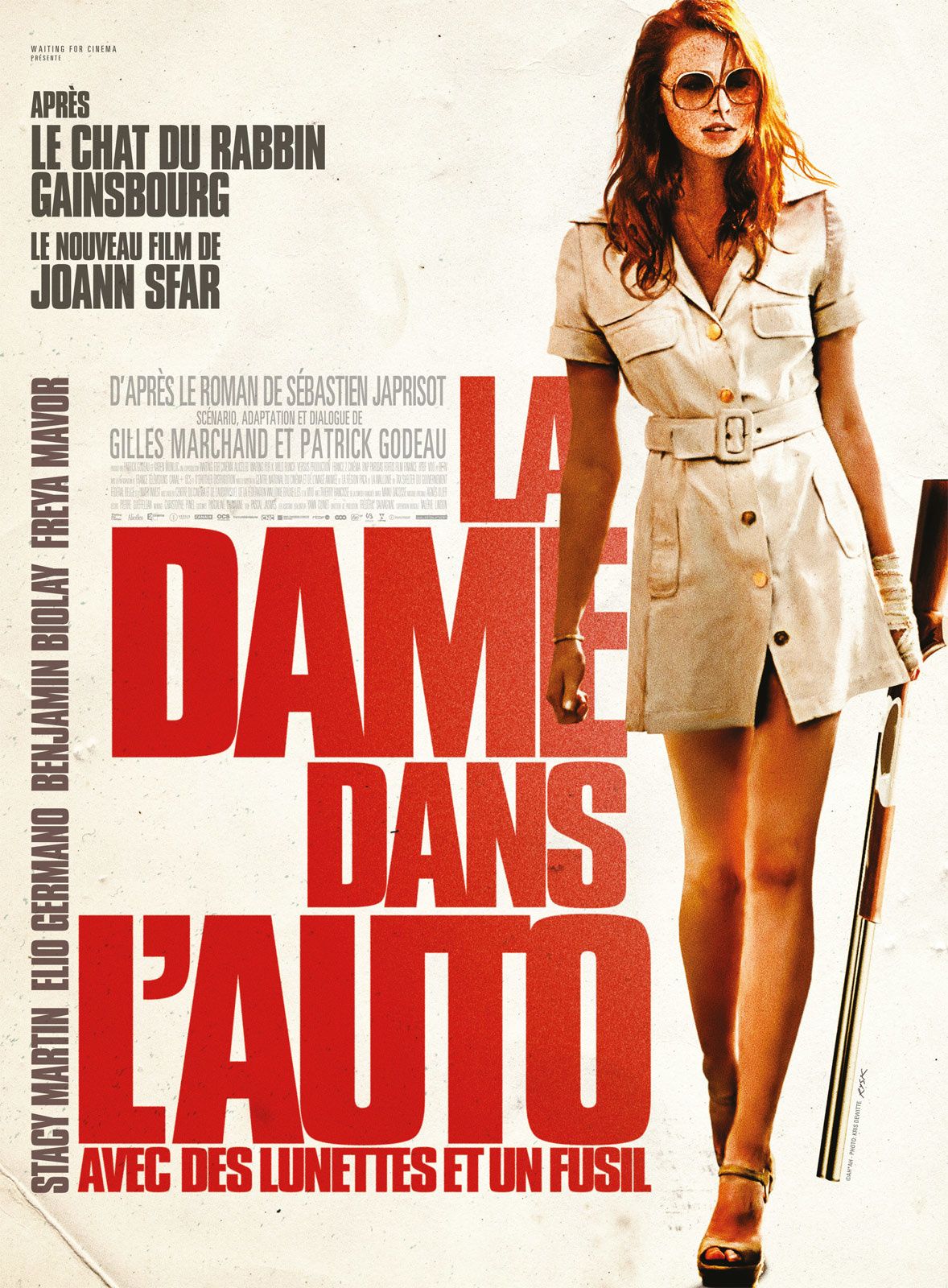 La dame dans l'auto avec des lunettes et un fusil.