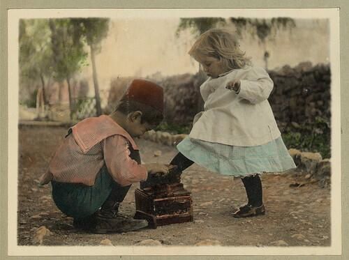 A young boy polishes his girlfriend's shoes