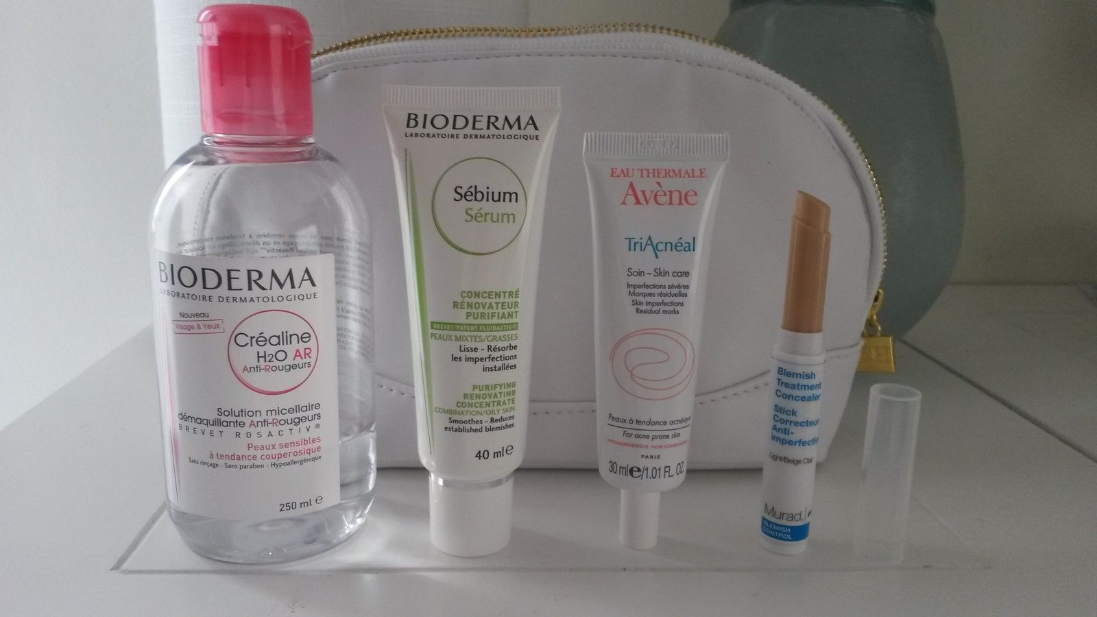 De gauche à droite : Solution micellaire démaquillante H20 Anti-Rougeurs Bioderma, Concentré rénovateur purifiant Sébium Sérum Bioderma, Soin TriAcnéal Avène, et Stick Correcteur anti-imperfections en teinte beige clair Murad 