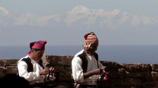 Indiens Quechoas de l’île de Taquilé, tricotant sur fond de lac Titicaca et sommets enneigés des Andes boliviennes.