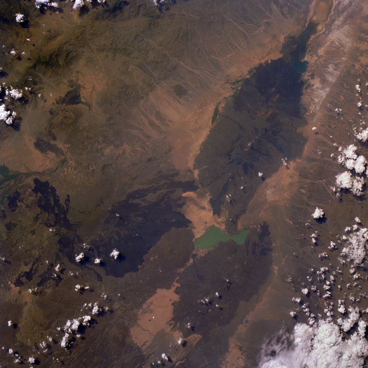 Le massif de l'Erta Ale - photo NASA  STS026-033-080 / 30.09.1988 - 11h35 GMT (L’ Erta Ale, un volcan situé dans la vallée du rift du nord de l’Ethiopie, est visible sur cette photo prise quasi à la verticale au nord du lac Afrera, de couleur turquoise. Le volcan, connu sous le nom de « montagne qui fume » par les tribus locales, possède un lac de lave actif (peu discernable sur la photo) d’approximativement 46 mètres de large, qui est en éruption quasi constante depuis la fin des années 60.)