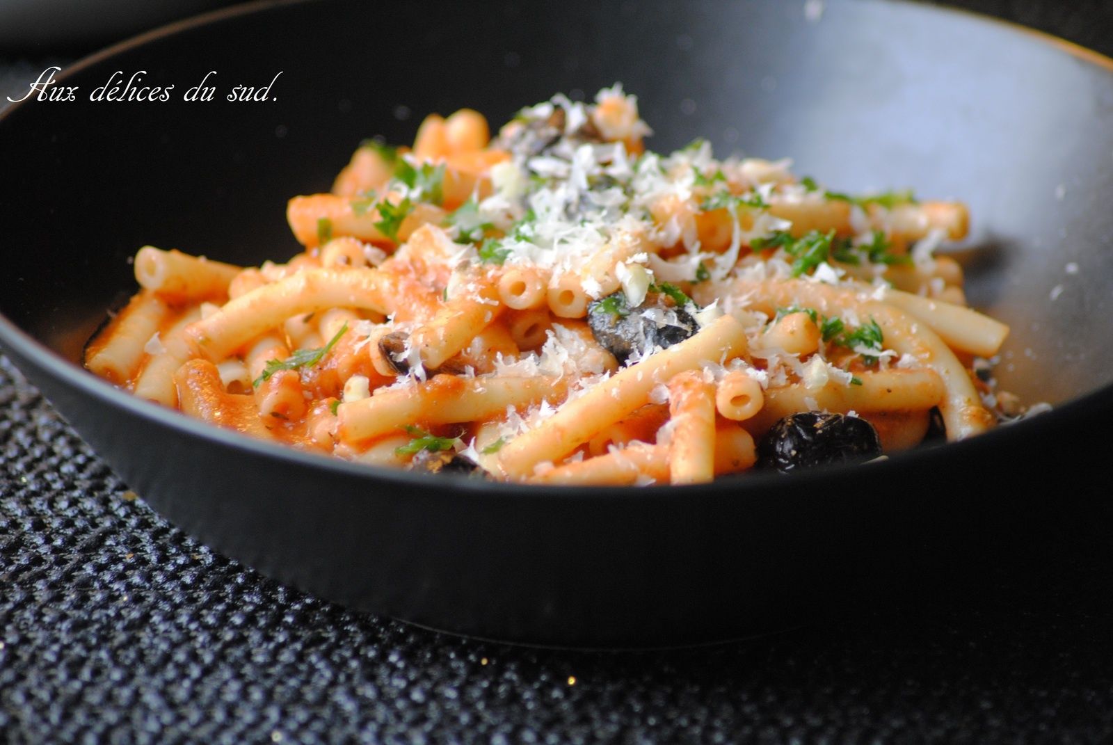 Macaroni à la sauce tomate , pesto , olives noires . Aux délices du sud
