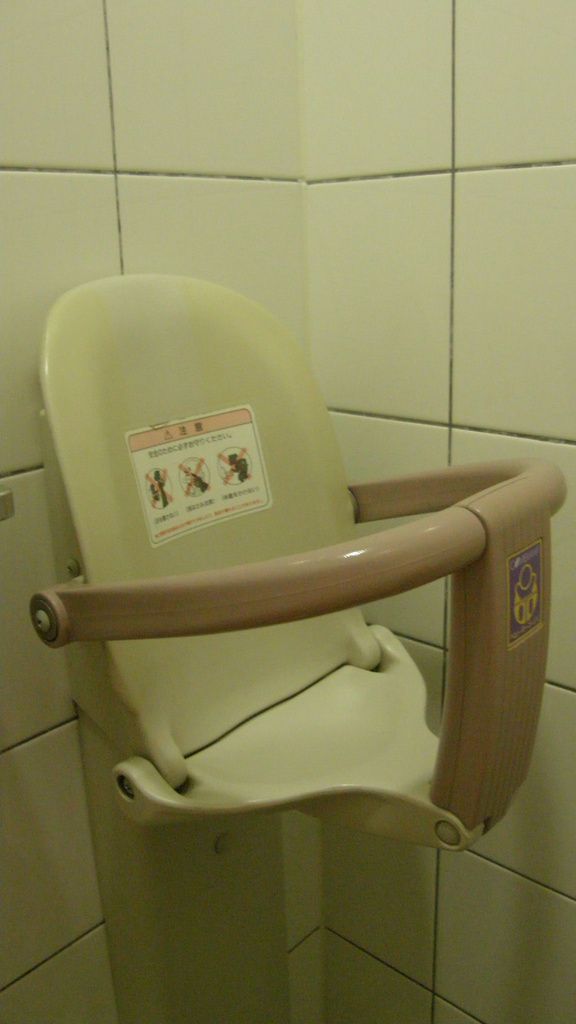 Un siège pour asseoir un bébé est fixé dans un angle, sorte de chaise haute, permettant à la maman (y va-t-il l’équivalent dans les toilettes des hommes ?) de surveiller son enfant pendant qu’elle vaque à ses « occupations ».