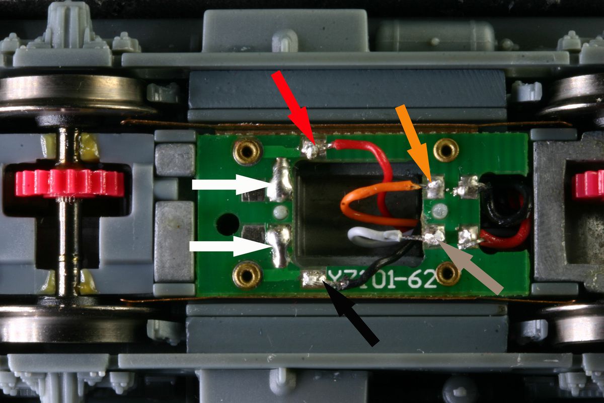 Faire passer les fils à travers la caisse et le chassis.  Suprimer les éléments électroniques et souder les fils du décodeur  (rouge noir,orange et gris)  il est inutile de rompre le contacte (flêches blanches).