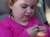 Karla beim Vernaschen ihrer selbstgebastelten Cheerioskette, während Mama das Auto aussaugt.