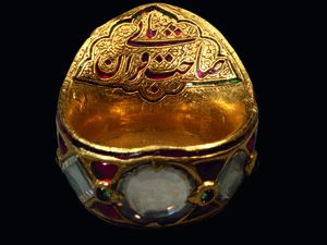 Bague d’archer de l’empereur Shah Jahan  Inde, vers 1625-1650  Or, diamants, rubis, émeraudes  Inscription en persan: Sahib qiran-i thani («Le  Second Maître de l’Heureuse  Conjonction»)  Saint-Pétersbourg, musée de l’Ermitage  © Musée national de l’Ermitage, Saint-Pétersbourg,  2017 /Vladimir Terebenin