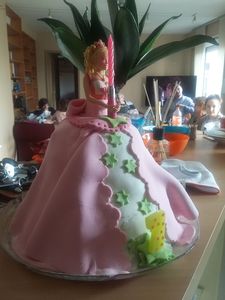 voici un gâteau avec une poupée de porcelaine et un décor en pâte à sucre