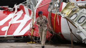 Un enquêteur d'Airbus marche, le 12 janvier 2015, à côté d'un morceau de l'avion d'AirAsia échoué en mer.