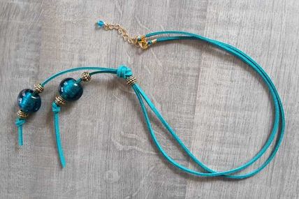 Collier suédine bleu vert et magnifiques perles de verre bleu accompagnées de perles métal ciselé doré.