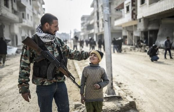 Un combattant kurde et son fils dans Kobané, libéré. Crédit photo: AFP.