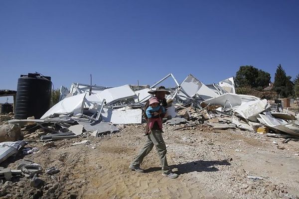 Foto : Palestina Bedueno portas sian junan infanon antaŭ sia loĝejo detruita de buldozoj, apud la israela kolonio Karmel, situanta en la vilaĝo Um Alkhier (proksime de Hebrono) en Cisjordanio, la 27an de oktobro 2014