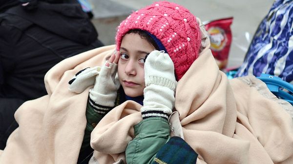 Afgana rifuĝintino sidanta en familiaj vestaĵoj