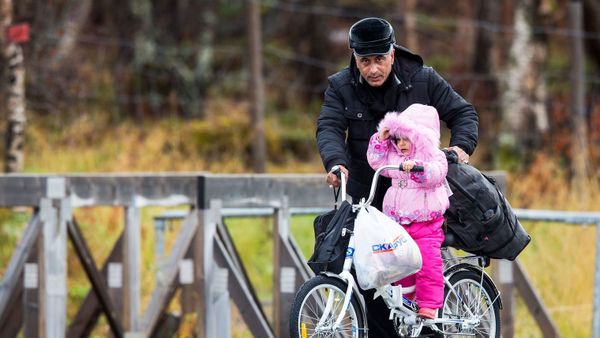 Viro helpas knabinon trapasi la landlimon inter Rusio kaj Norvegio ĉe la doganejo Storskog la 13an de oktobro 2015. afp.com/Tore Meek
