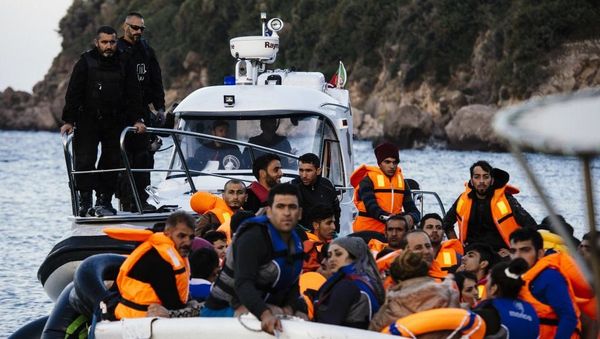 Portugalaj marbordaj gardistoj el la agentejo Frontex eskortas migrantojn kaj rifuĝintojn apud la greka insulo Lesbo, la 18an de oktobro 2015. AFP PHOTO / DIMITAR DILKOFF