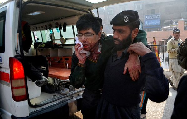 Un élève de l'école, blessé lors de l'attaque, est évacué par les forces de l'ordre (Mohammad Sajjad/AP).