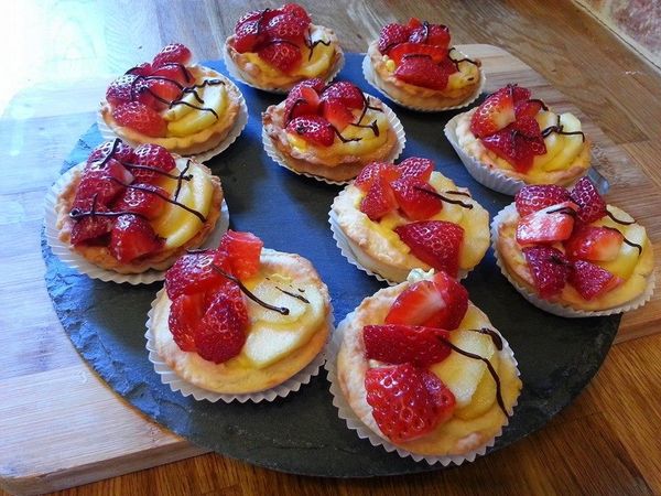 Les tartelettes à la créme pâtissière avec des fraises et des pommes caramélisées