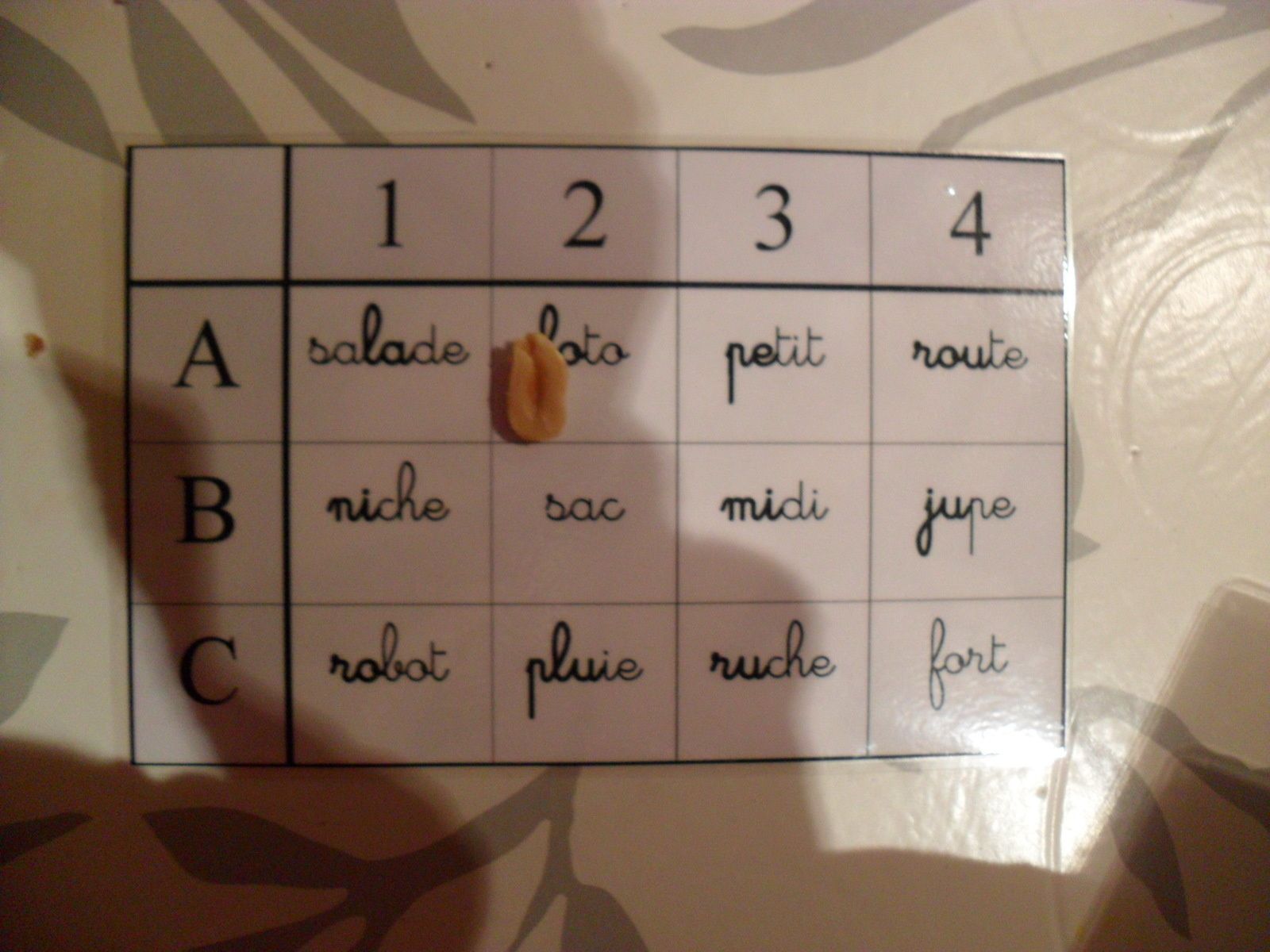 Il lit "salade". S'il a juste, il peut poser un pion sur le mot "salade". Ici, les pions sont des cacahuètes (motivation suplémentaire en attendant le repas! Quand le jeu est fini, il peut manger les cacahuètes.)