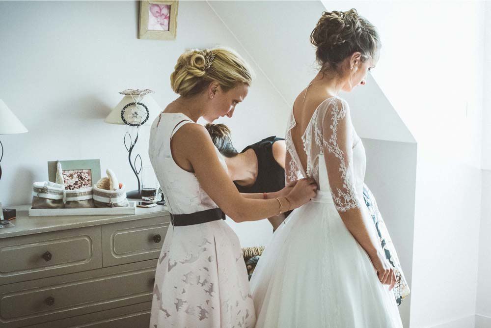 Les deux soeurs de la mariée l'aident à s'habiller et mettre sa robe. Un moment d'intimité plein d'émotions que j'ai aimé photographier