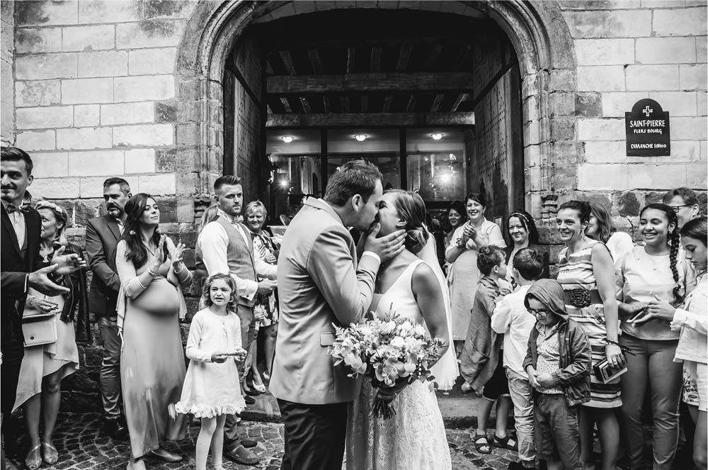 Alex et Fanny s'embrassent devant l'église. Photo de yann lecomte, photographe de mariage à Lille. 