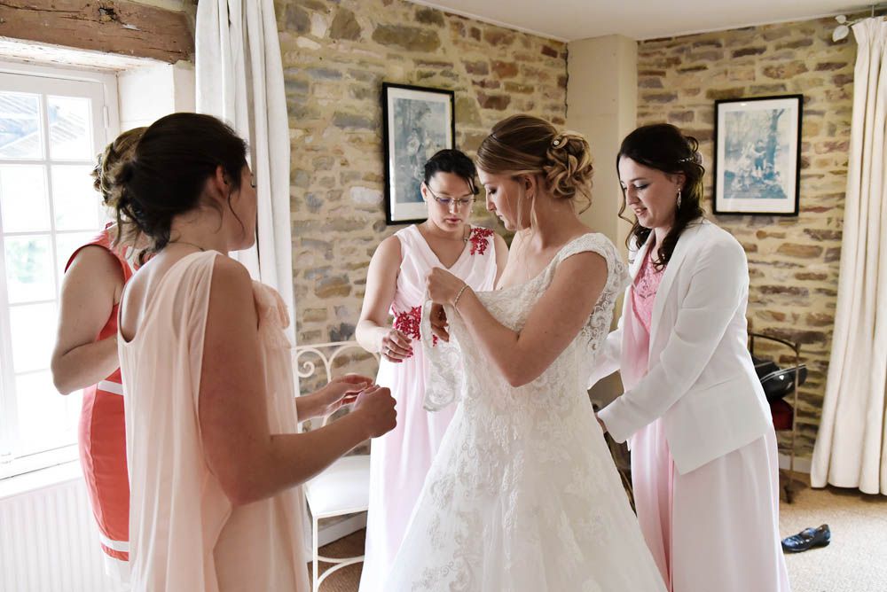 les témoins et la maman autour de la mariée pour l'aider à se préparer et enfiler sa jolie robe