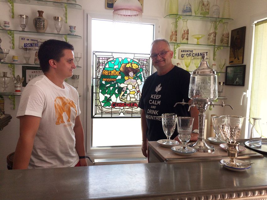 Patrick et Quentin derrière leur bar avec installé sur la fenêtre le vitrail publicitaire Cusenier de l'école de Nancy. Sur les étagères, carafes gravées et verres. Ph. Delahaye.