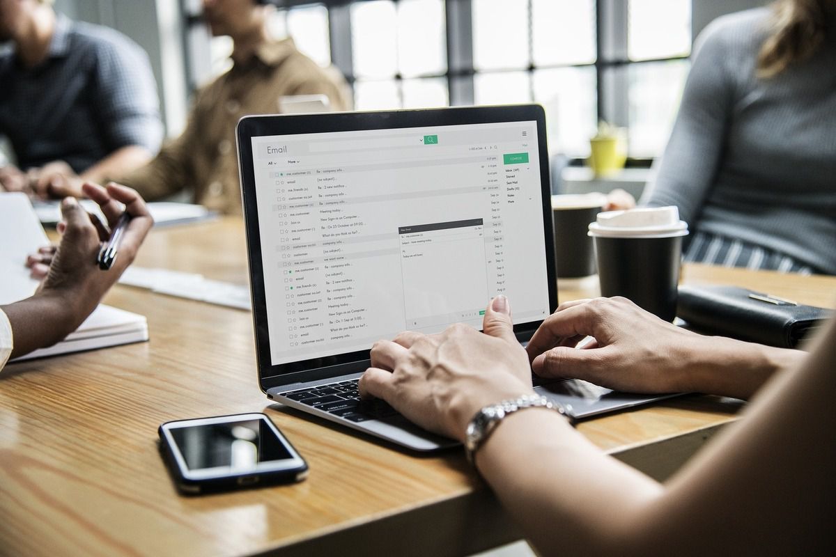 mains de femme qui semble écrire un mail sur un ordinateur portable lors d'une réunion professionnelle