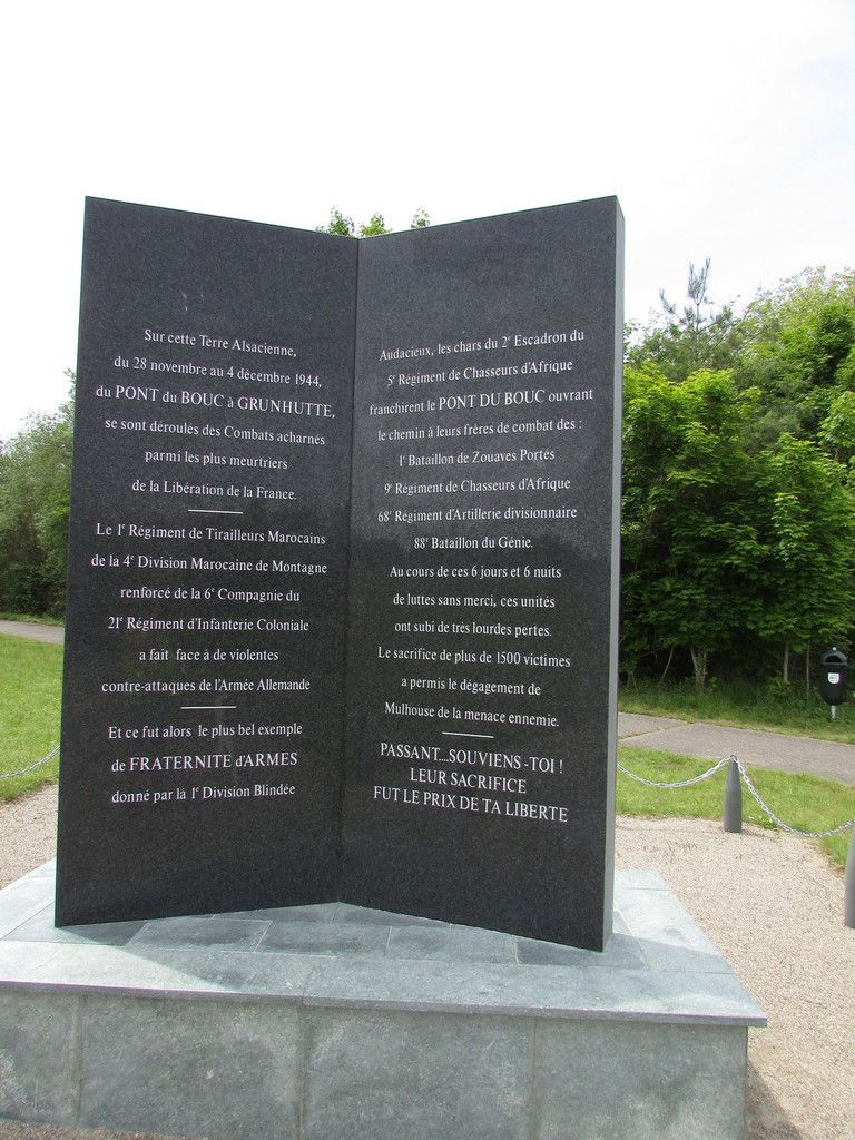 Sur cette terre Alsacienne du 28 novembre au 4 décembre 1944, du PONT du BOUC à GRUNHUTTE, se sont déroulés des Combats acharnés parmi les plus meurtriers de la Libération de la France. Le premier régiment de tirailleurs Marocains de la 4è division Marocaine de Montagne renforce de la 6è Compagnie du 21è Régiment d'Infanterie Coloniale a fait face de de violentes contre-attaques de l'Armée Allemande. Et ce fut alors le plus bel exemple de FRATERNITÉ D'ARMES donnée par la 1e division blindée. Audacieux, les chars du 2è escadron du 5è Régiment de Chasseurs d'Afrique franchirent le Pont du Bouc ouvrant le chemin à leurs frères de combat des 1e Bataillon de Zouaves Portés 9e Régiment de Chasseurs d'Afrique 68e Régiment d'Artillerie divisionnaire 88e Bataillon du Génie. Au cours de ces 6 jours et 6 nuits de lutte sans merci ces unités ont subi de très lourdes pertes. Le sacrifice de plus de 1500 victimes a permis le dégagement de Mulhouse de la menace ennemie. PASSANT... SOUVIENS-TOI ! LEUR SACRIFICE FUT LE PRIX DE TA LIBERTÉ
