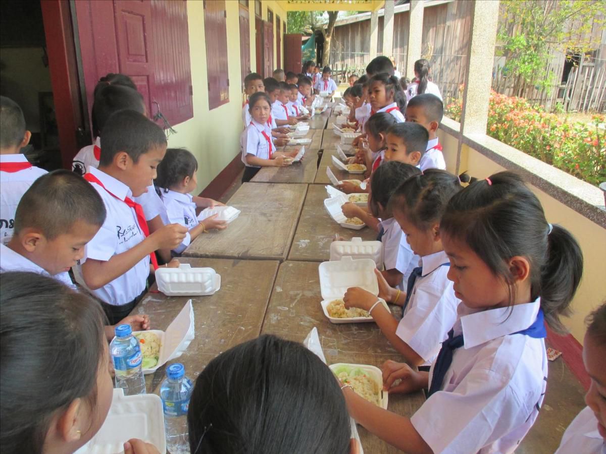 Les élèves se régalent du repas offert par la Toupie, à savoir un plat de riz accompagné de légumes et poulet et un "capia".