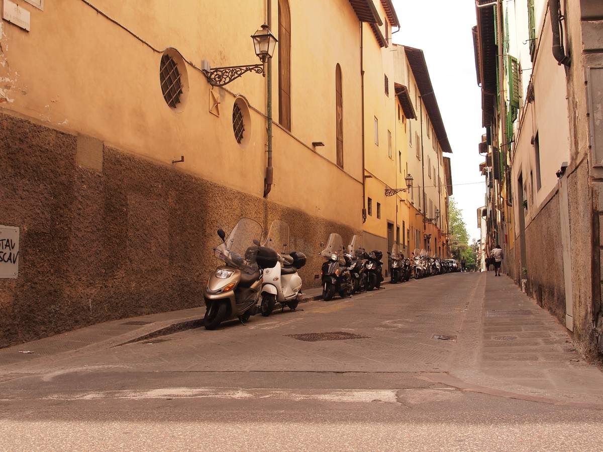 Une ruelle avec un alignement de scooters.