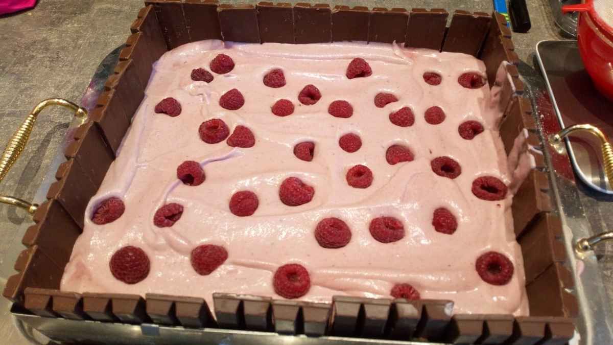 recette pour un gâteau 30/27 (20 personnes ) : 1) préparez un biscuit cuillère de façon à faire un rectangle de 30/27 et un autre 25/22 , montez 180 g de blanc en neige , bien les serrer avec 150 g de sucre , ajoutez 120 g de jaunes d'oeuf + 150 g de farine 2) à l'aide d'une poche à douille pocher les deux rectangles et faire cuire à 180° pendant 10 min 3) laissez refroidir 4) commencez à monter votre entremet , mettre le grand rectangle dans un rectangle à pâtisserie de 30/27 puis installer les kit kat mini tout autour ( pour rappeler les barriques) 5) préparez l'entremet framboise , faire ramollir 14 g de gélatine , faire chauffer 360 g de pulpe de framboise , y ajouter la gélatine . Montez 400 g de crème liquide à 30% en crème fouettée , puis mélanger le coulis de fruits (attention il doit être refroidi) , verser la préparation sur le fond de votre gâteau (comme sur la photo) puis y installer des framboises fraîches et mettre au frais pour que la crème durcisse 6) préparez une feuillantine faire fondre 100 g de chocolat au micro onde ,y ajouter 1 c à soupe de praliné maison (voir recette sur le blog) . Incorporer 1 paquet de gavotte ( le chocolat ne doit pas être trop chaud sinon cela va ramollir vos biscuits) . Etendre entre deux feuilles de papier sulfurisé cette feuillantine de la forme du rectangle 7) installez cette feuillantine sur l'entremet (il faut que la crème soit un peu ferme) 8) installez votre deuxième rectangle , l'imbiber d'un sirop de sucre au kirsch 9) préparez une crème fouettée mascarpone avec 400 g de crème liquide + 250 g de mascarpone + 60 g de sucre glace + vanille en poudre 10) dressez la moitié de cette crème dessus le biscuit , y installer des raisins ( ceux là proviennent de la vigne de mon petit frère d'ou le nom du gâteau) 11 ) avec l'autre parti de la crème , sur la moitié du gâteau , pochez la crème à l'aide d'une douille taille 10 12) sur l'autre moitié du gâteau, garnir de raisins frais et les glacer à la gelée de mirabelle 13) décoration thème les vendanges ,utilisation des bouchons , des feuilles de vigne et d'une grappe ... Et voilà un gâteau frais, gourmand qui ravira vos convives