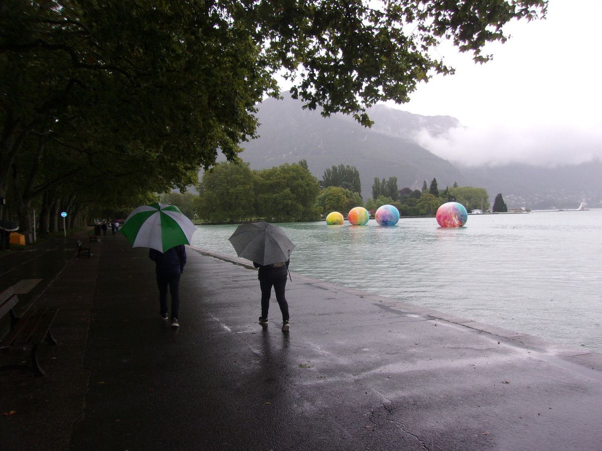 Deux personnes marchent sous la pluie au bord du lac d'Annecy 