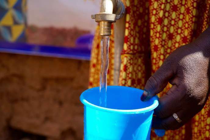Ramata Drabo, une habitante de Tougan, dans le nord-ouest du Burkina Faso, se sert du robinet d’eau potable récemment installé à l’entrée de sa cour. Sophie Douce