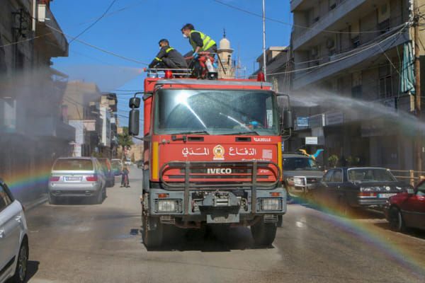 AFP Des membres de la défense civile diffusent du désinfectant dans les rues de Baalbeck, le 16 mars 2020 © AFP - -