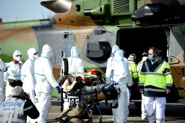 Des équipes médicales transportent un patient contaminé par le Covid-19 pour l'évacuer à bord d'un hélicoptère vers l'hôpital d'Essen, en Allemagne, le 28 mars 2020 sur un parking près du CHR de Metz © AFP - JEAN-CHRISTOPHE VERHAEGEN