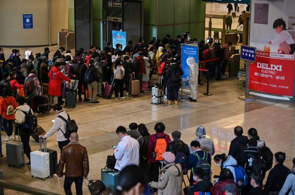 Des voyageurs font la queue pour passer au contrôle de leur température et de leur identité à leur arrivée à la gare de Wuhan, dans la province chinoise du Hubei, le 28 mars 2020 © AFP - HECTOR RETAMAL