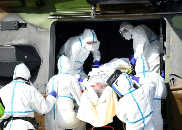Des équipes médicales transportent un patient contaminé par le Covid-19 pour l'évacuer à bord d'un hélicoptère vers l'hôpital d'Essen, en Allemagne, le 28 mars 2020 sur un parking près du CHR de Metz © AFP - JEAN-CHRISTOPHE VERHAEGEN