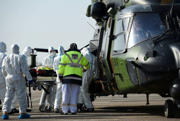 Des équipes médicales transportent un patient contaminé par le Covid-19 pour l'évacuer à bord d'un hélicoptère vers l'hôpital d'Essen, en Allemagne, le 28 mars 2020 sur un parking près du CHR de Metz © AFP - JEAN-CHRISTOPHE VERHAEGEN