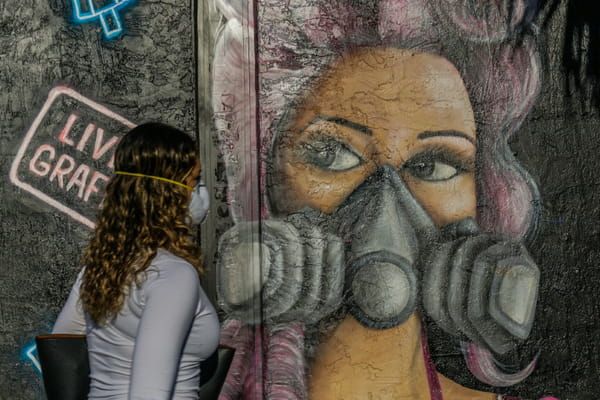 Une femme passe devant une fresque murale dans un quartier de Miami, le 3 avril 2020 © AFP - CHANDAN KHANNA