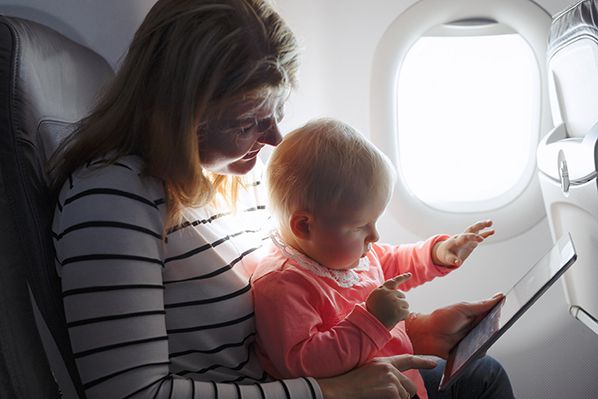 Mother and baby using tablet on flight - Shutterstock