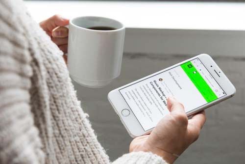 Une personne lit les actualités sur son smartphone en sirotant un café